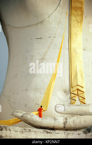 Un moine debout sur la paume de la statue du Grand Bouddha, il s'apprête à emballer robe jaune autour de la statue. Banque D'Images
