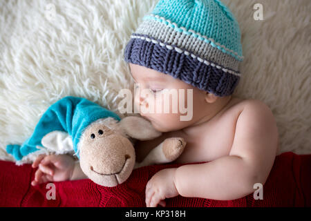 Peu dormir bébé nouveau-né garçon, vêtu d'étoffes hat, holding toy Banque D'Images