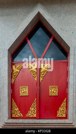 Volets rouge décoré d'ornements d'or sur un temple en Thaïlande closeup Banque D'Images