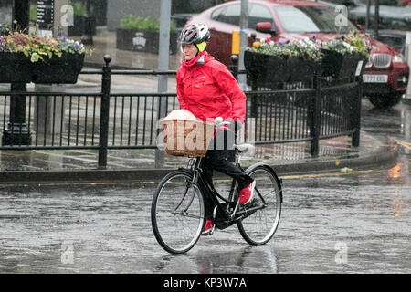 Vélo femme dans de fortes pluies dans la région de Southport, Merseyside, Météo France. Après un week-end de froid glacées, shoppers Noël brave la pluie diluviennes comme ils s'aventurer dans le centre-ville de Southport. De fréquentes averses hivernales continuera la nuit, tournant parfois en rafales de neige s'accumuler sur les collines. Credit : Cernan Elias/Alamy Live News Banque D'Images