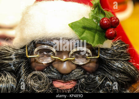 African American Santa Claus Doll avec des lunettes et des cerises sur son chapeau - gros plan extrême Banque D'Images