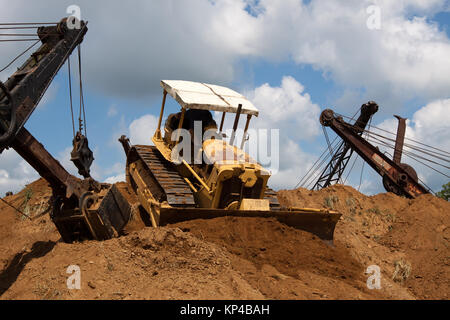 Un vieux bulldozer poussant hors du sol au sommet d'un stock énorme. Banque D'Images