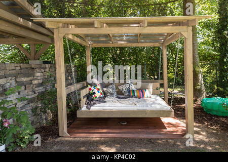 Big swing piscine lit. Chaise longue dans le jardin dans la pergola. Lit de jardin avec coussins. Grand lit d'extérieur pour bronzer et se reposer. Quatre lit de jardin. Banque D'Images