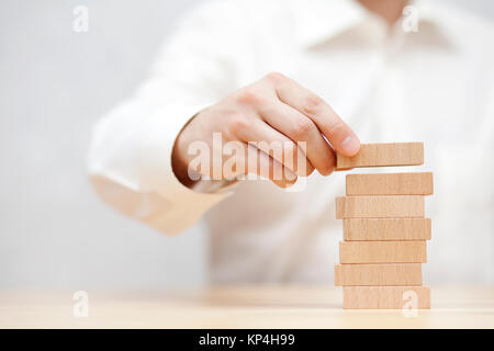 La main de l'homme l'empilement des blocs de bois. Concept de développement des entreprises. Banque D'Images