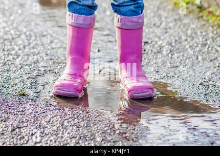 Little girl with pink wellys dans la flaque sur la rue Banque D'Images