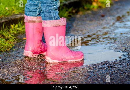 Little girl with pink wellys dans la flaque sur la rue Banque D'Images