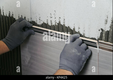 Pose de carreaux en céramique. Carreleur carrelage mural en céramique mise en place sur l'adhésif Banque D'Images