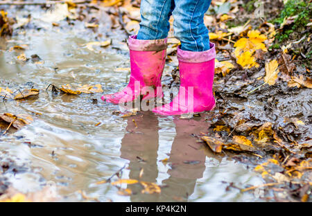 Little girl with pink wellys dans la flaque sur la forêt Banque D'Images