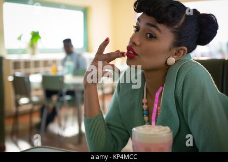 Young woman sitting on couch smiling dans le restaurent Banque D'Images