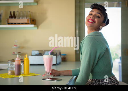 Portrait of smiling woman holding milkshake à la caméra en verre au restaurant Banque D'Images