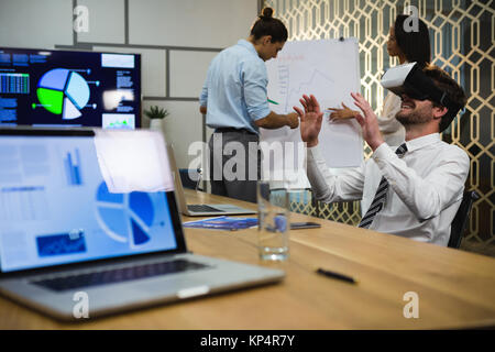 Portrait casque de réalité virtuelle alors que collègues discutant sur flip chart in office Banque D'Images