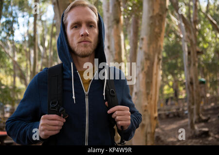 Portrait de jeune homme randonneur avec sac à dos, debout dans la forêt lors d'une journée ensoleillée Banque D'Images