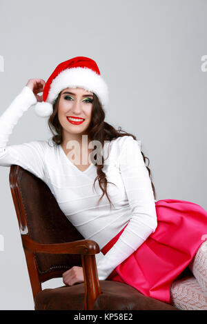 Portrait de jeune femme assis sur une chaise à santa hat, isolé Banque D'Images