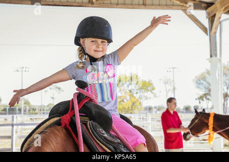 Jolie petite fille assise sur un cheval. Horse and jockey petit - cute little girl in pink pantalon avec un casque et son meilleur ami Banque D'Images