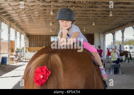 Jolie petite fille assise sur un cheval. Horse and jockey petit - cute little girl in pink pantalon avec un casque et son meilleur ami Banque D'Images