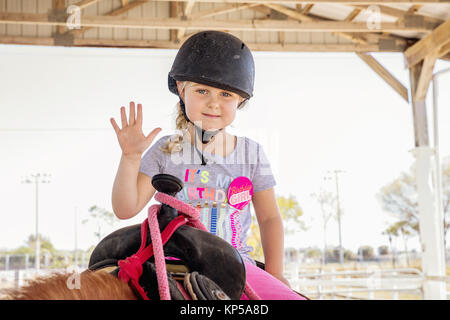 Jolie petite fille assise sur un cheval. Horse and jockey petit - cute little girl in pink pantalon avec un casque et son meilleur ami Banque D'Images