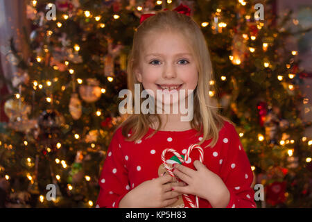 L'âge scolaire adorable girl holding up cannes de bonbons en forme de coeur pour la saison de vacances de Noël Banque D'Images