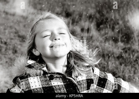 Belle jeune fille debout dans le champ ouvert comme la neige commence à tomber dans l'hiver Banque D'Images