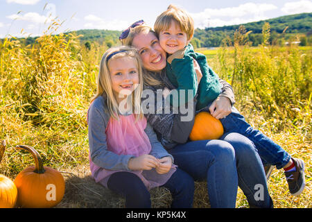 Mère avec son fils et sa fille assis avec des citrouilles sur farm Banque D'Images