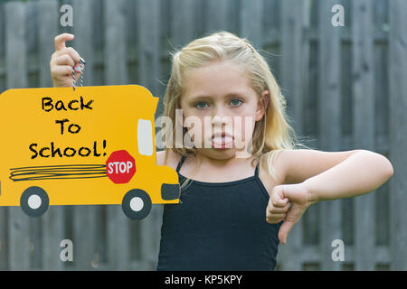 Adorable fille d'âge scolaire de froncer et holding première journée d'école sign Banque D'Images