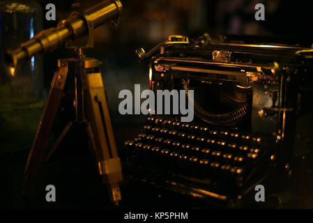 Petit télescope vintage debout sur la table en bois à côté de vieille machine à écrire noire Banque D'Images