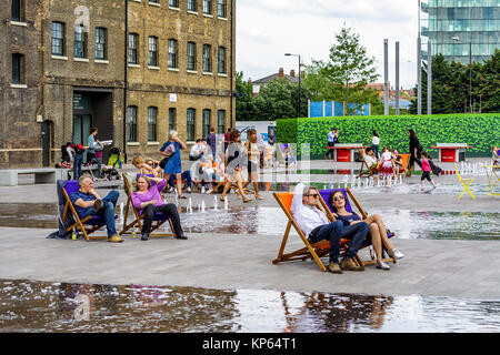 Les gens vous relaxant dans des chaises longues entre les fontaines dans le grenier Square, King's Cross, Londres, Royaume-Uni, 2014 Banque D'Images