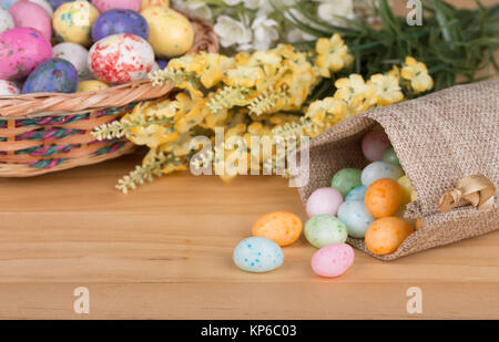 Oeufs de Pâques colorés de bonbons dans un sac de tissu sur une surface en bois Banque D'Images