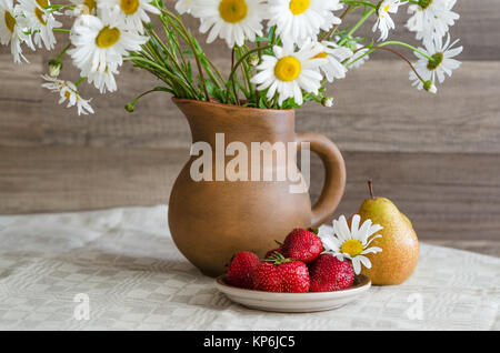 Bouquet de marguerites dans un pot en argile et des fraises avec des poires. Pays Still Life Banque D'Images