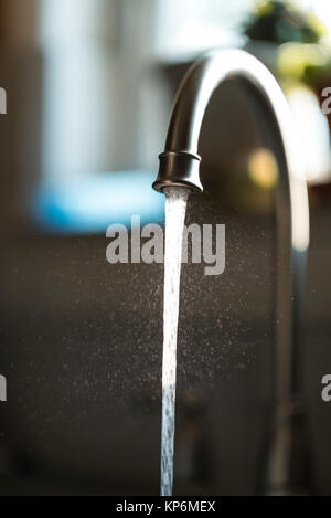 Libre de gouttelettes d'eau de robinet de cuisine de flux liquide, isolé par l'arrière-plan blured Banque D'Images