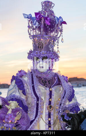 Carnaval de Venise, Vénétie, Italie 2017 femme en costume violet classique au coucher du soleil avec ciel orange sur le lagon Banque D'Images