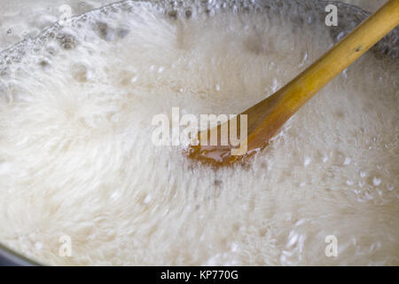 Cuillère en bois en remuant rapidement liquide bouillant close up en casserole - texture mouvement Fractal Banque D'Images