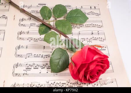 Une rose rouge sur une vieille partition de musique Banque D'Images