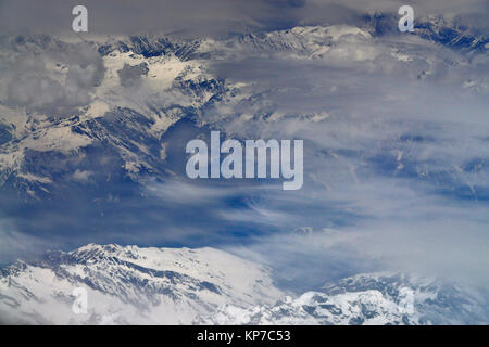 Hautes montagnes enneigées, prises à partir d'un avion, les sommets sont couverts de brouillard et de nuages, l'hiver dans l'Himalaya. Banque D'Images