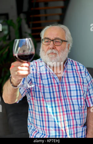 Mature man drinking wine at home Banque D'Images