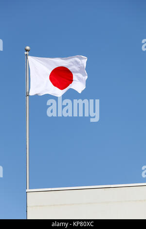 Drapeau japonais en vent contre un ciel bleu Banque D'Images