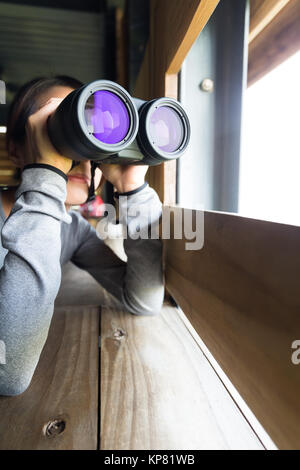 Jeune femme l'utilisation de la maison en bois au binoculaire Banque D'Images