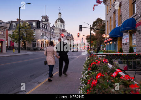 Un couple de touristes en passant par les bâtiments historiques le long de la rue Ontario avec l'Hôtel de ville dans la distance au centre-ville de Kingston, Ontario, Canada. Banque D'Images