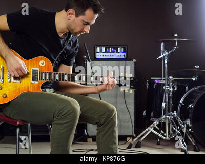 Le guitariste assis et jouant sur scène Banque D'Images