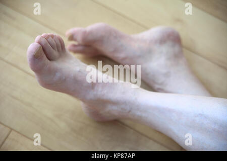 Man croise les jambes sur le plancher Banque D'Images