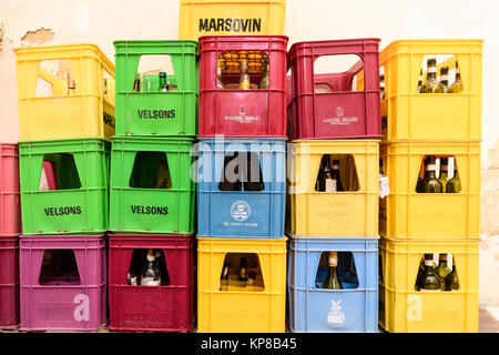 Caisses multicolores avec des bouteilles en verre vide en attente de collection à l'extérieur d'un bar pour le recyclage. Banque D'Images