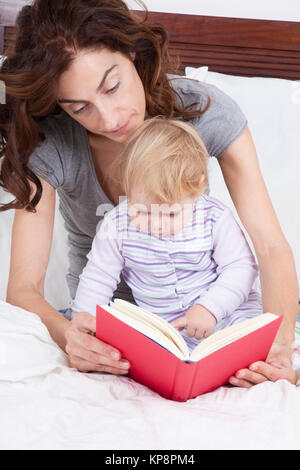 Bébé et maman lire au lit Banque D'Images