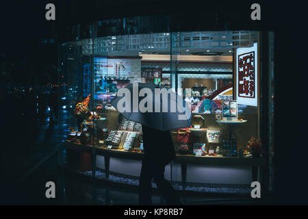 Old man holding umbrella marchant devant un magasin à Tsukiji, Tokyo, Japon Banque D'Images