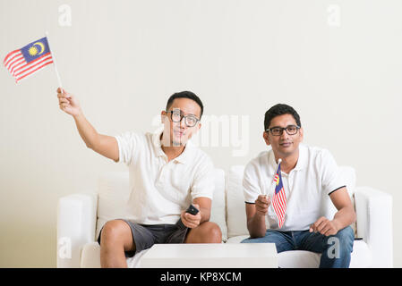 Les hommes de Malaisie La Malaisie avec flag regarder du sport à la télévision Banque D'Images