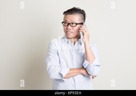 Mature Asian man talking on smartphone Banque D'Images