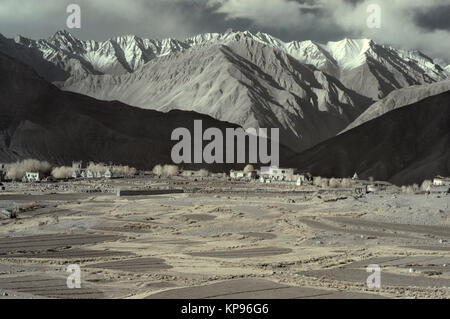 Village dans les montagnes : parmi la vaste gorge sur l'arrière-plan de montagnes de la nuit il y a de petites huttes blanc de la paysannerie, dans l'avant-plan Banque D'Images