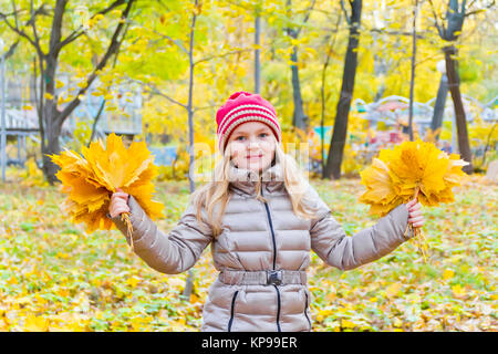 Jolie fille avec des bouquets de feuilles en automne Banque D'Images