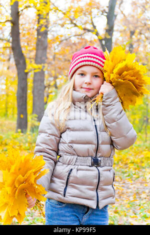 Jolie fille avec des bouquets de feuilles en automne Banque D'Images