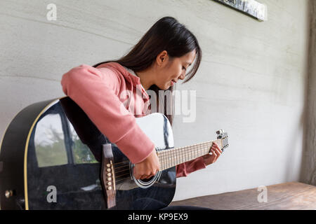 Asian Woman jouer avec une guitare à la maison Banque D'Images