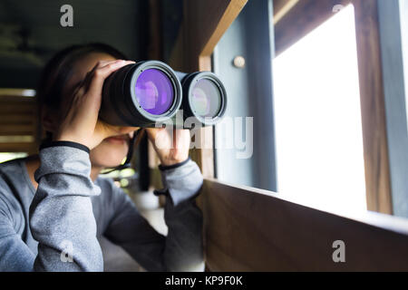 Jeune femme d'utiliser le télescope sur maison en bois Banque D'Images