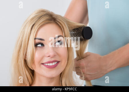 Hairstylist Brushing Woman's Hair At Salon Banque D'Images